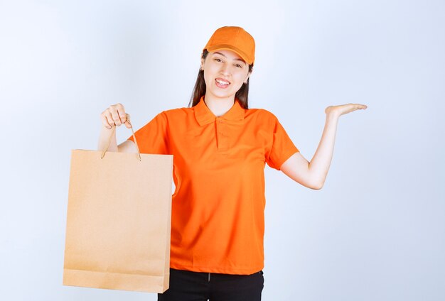 Agent de service féminin en code vestimentaire de couleur orange tenant un sac à provisions en carton