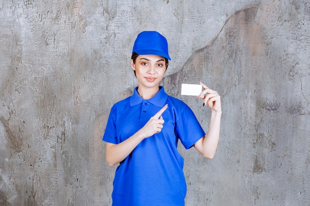 Agent de service féminin en uniforme bleu présentant sa carte de visite.