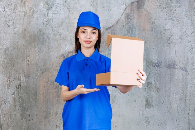 Agent de service féminin en uniforme bleu tenant une boîte en carton ouverte.