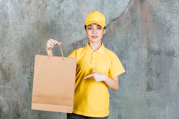 Agent de service féminin en uniforme jaune tenant un sac à provisions.