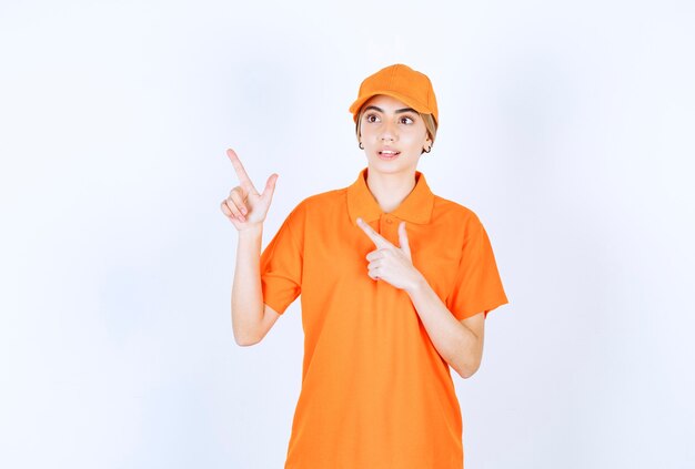 Agent de service féminin en uniforme orange pointant vers quelque chose au-dessus avec des émotions