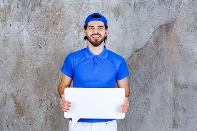 Agent de service masculin en uniforme bleu tenant un panneau d'information rectangulaire.