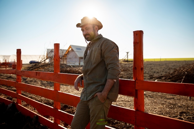 Agriculteur posant à côté d'une clôture à la ferme