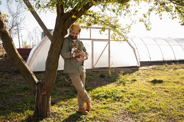 Agriculteur posant à côté de sa serre à la ferme