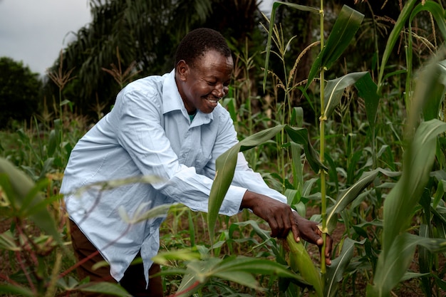 Agriculteur souriant à plan moyen dans un champ de maïs