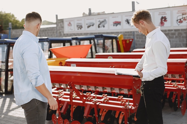 Photo gratuite agronome choisissant un nouveau planteur. homme au sol extérieur de la boutique. machines agricoles.