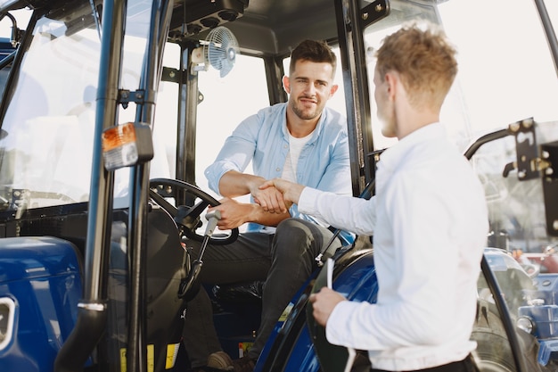 Photo gratuite agronome choisissant un nouveau planteur. homme au sol extérieur de la boutique. machines agricoles.