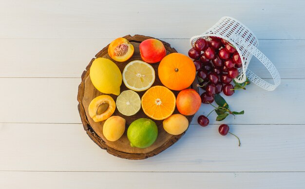 Agrumes aux cerises, abricots, nectarines à plat sur une planche à découper et fond en bois