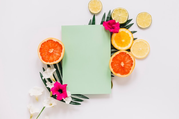 Agrumes et fleurs près de la feuille de papier sur la feuille