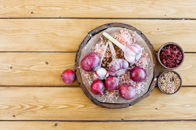 Photo gratuite ail aux oignons rouges, barberries séchées, sel gemme, quinoa, poivre noir à plat sur planche de bois et planche à découper