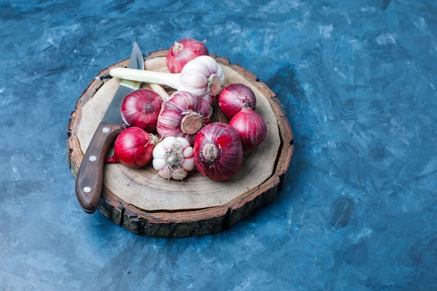 Photo gratuite ail aux oignons rouges, couteau sur planche grungy bleu et bois, high angle view.