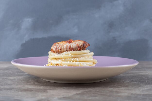 Aile de poulet sur spaghetti sur l'assiette, sur le marbre.