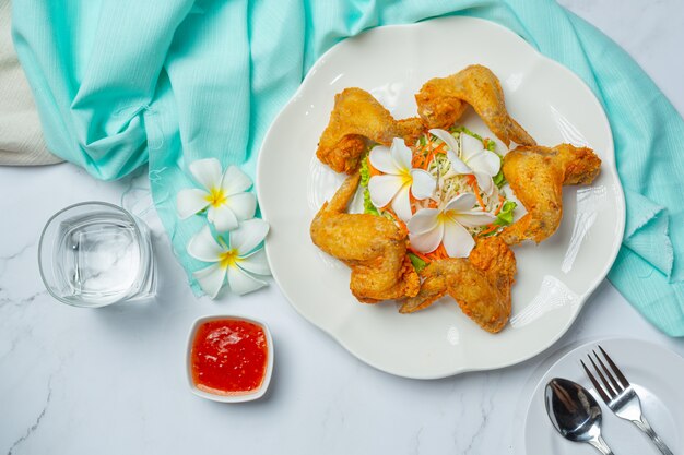 Ailes frites avec sauce au poisson, joliment décorées et servies.