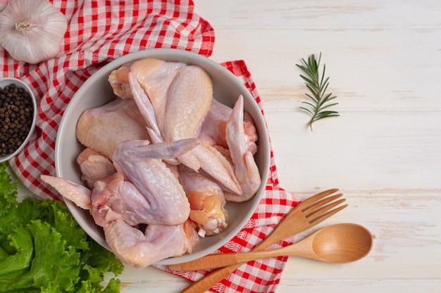 Ailes de poulet crues sur la surface en bois blanche.