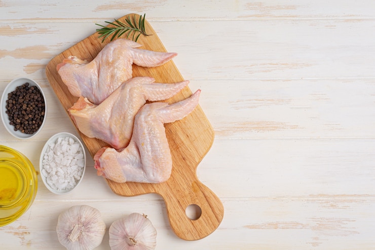 Photo gratuit ailes de poulet crues sur la surface en bois blanche.