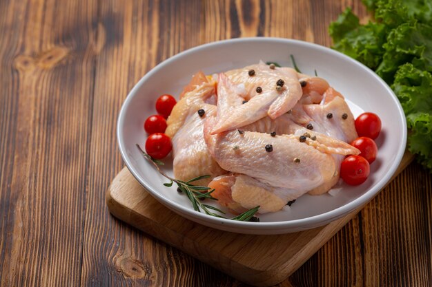 Ailes de poulet crues sur la surface en bois sombre.