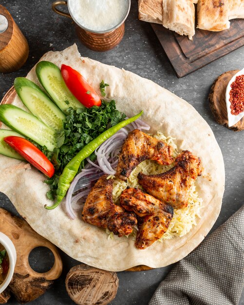 Ailes de poulet frites servies avec salade fraîche et oignons