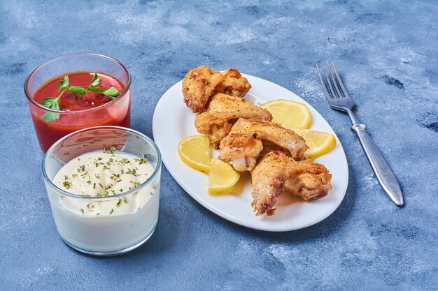 Ailes de poulet frites et servies avec des sauces.