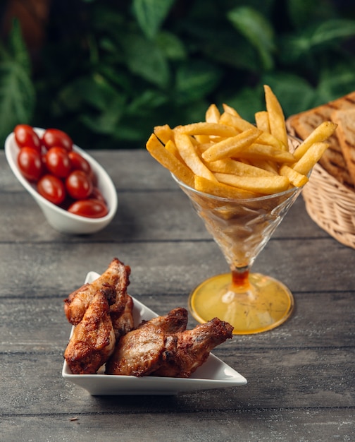 Photo gratuite ailes de poulet grillées avec frites et tomates cerises