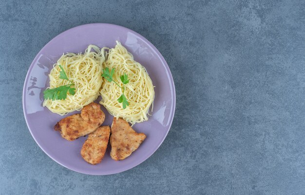 Ailes de poulet grillées et spaghettis sur plaque violette.