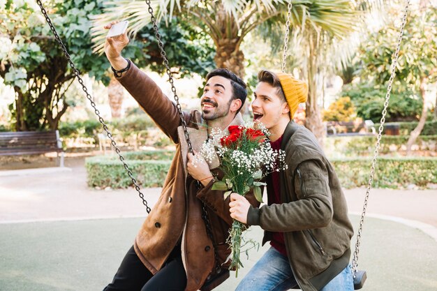 Aimer les hommes prenant selfie avec bouquet