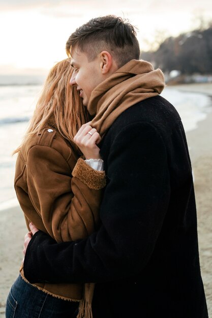 Aimer le jeune couple embrassant sur la plage en hiver