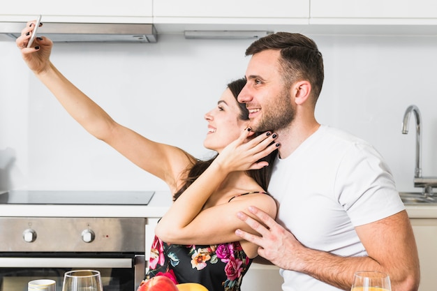 Aimer, jeune couple, prendre, selfie, sur, téléphone portable, dans cuisine