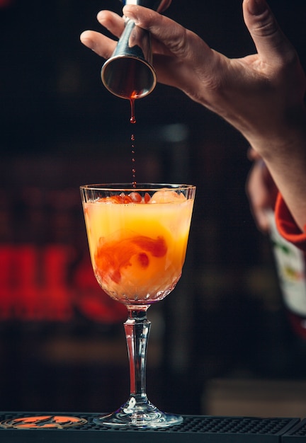 Ajout de sirop rouge dans un cocktail à l'orange.