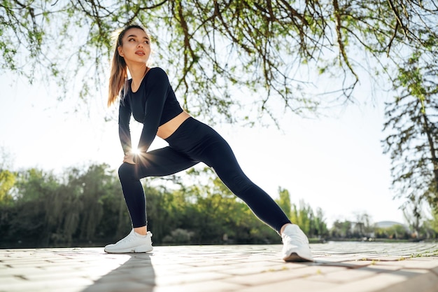 Ajuster la jeune fille en vêtements de sport bleu foncé exerçant dans le parc