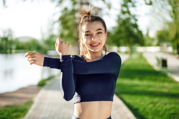 Ajuster la jeune fille en vêtements de sport bleu foncé exerçant dans le parc