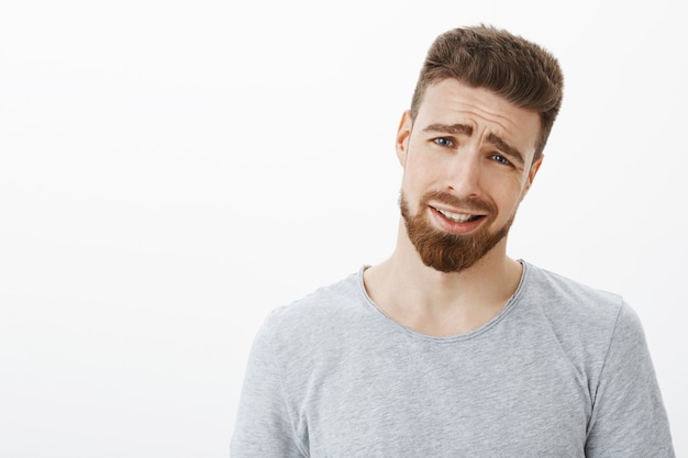 Allez mec, c'est nul. Bel homme d'affaires mécontent et mécontent avec barbe et yeux bleus, tête inclinée et fronçant les sourcils, plissant les sourcils et resserrant le sourire d'insatisfaction et de réticence