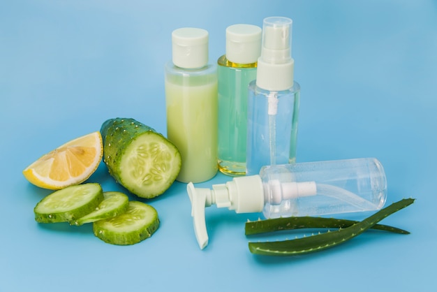 Photo gratuite aloe vera frais; tranches de citron et de concombre vaporisateurs sur fond bleu