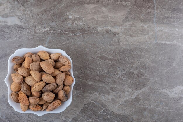 Amandes délicieuses dans le bol sur la surface en marbre