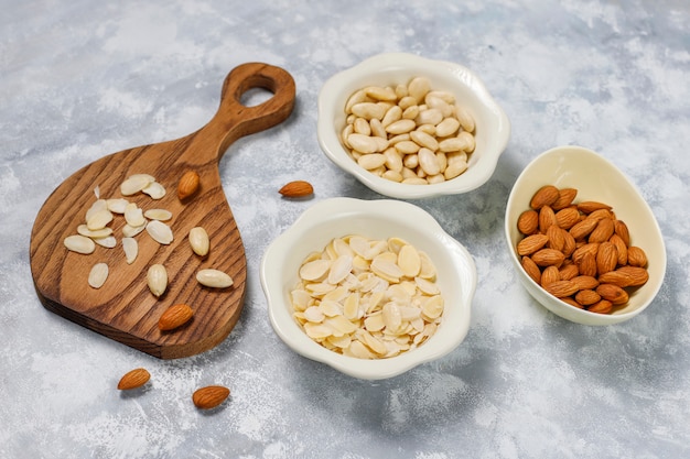 Photo gratuite amandes entières pelées (blanchies) et non blanchies dans des bols en céramique sur du béton gris