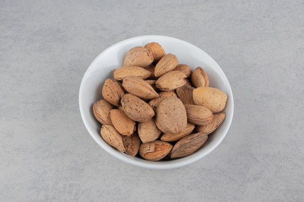 Amandes savoureuses dans le bol, sur la surface en marbre