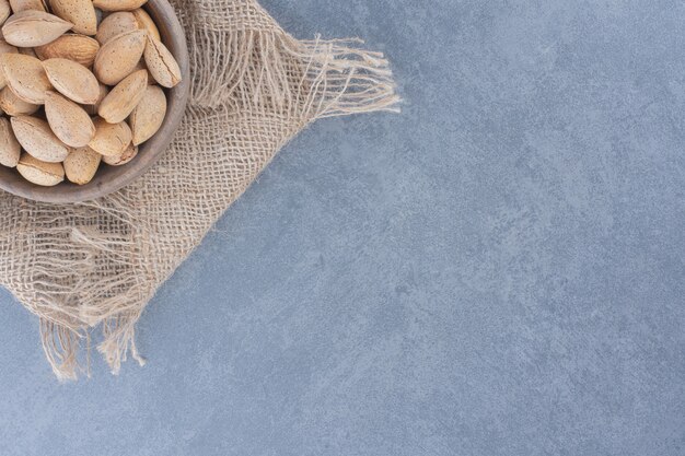 Des amandes savoureuses s'échappent d'un bol, sur le fond de marbre.