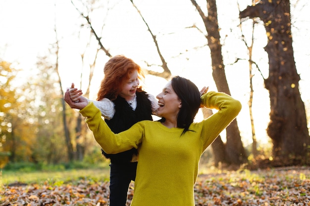 Photo gratuite ambiance d'automne, portrait de famille. charmante maman et sa fille aux cheveux roux s'amusent assises sur le tombé