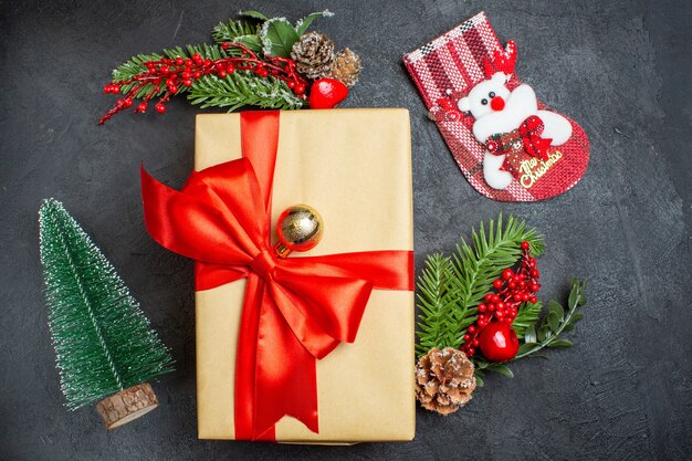 Ambiance de Noël avec de beaux cadeaux avec ruban en forme d'arc et accessoires de décoration de branches de sapin chaussette de Noël sur une table sombre
