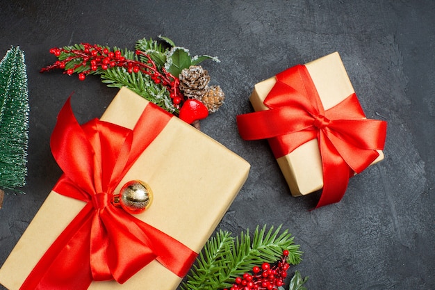 Ambiance de Noël avec de beaux cadeaux avec ruban en forme d'arc et accessoires de décoration de branches de sapin sur fond sombre