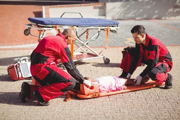 Photo gratuite les ambulanciers mettent une fille blessée sur un panneau