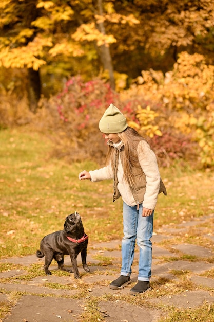 Avec un ami. Une jolie fille jouant avec son chien dans le parc