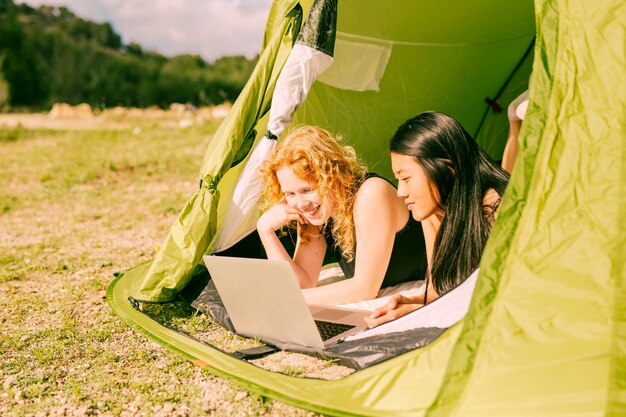 Amies à l&#39;aide d&#39;un ordinateur portable dans une tente