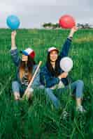 Photo gratuite amies avec des ballons dans des casquettes colorées rire dans le parc