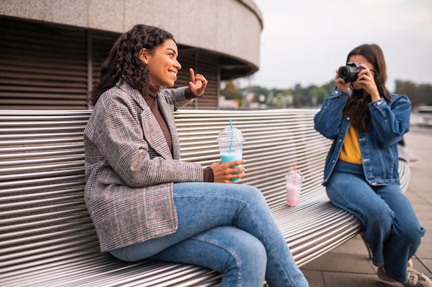 Amies à l'extérieur avec appareil photo et milkshake