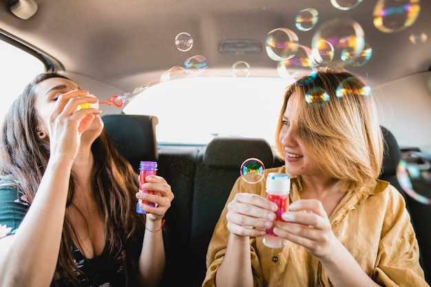 Amies soufflant des bulles dans le véhicule