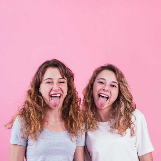 Photo gratuite des amies tirant la langue sur fond rose