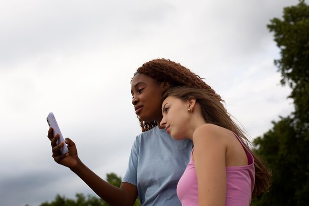 Amis adolescents utilisant un smartphone à l'extérieur