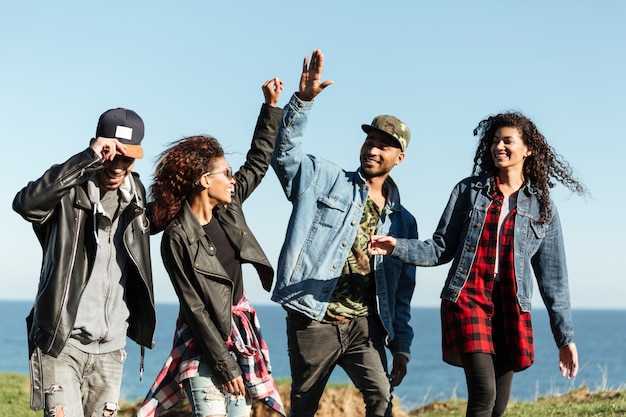 Des amis africains souriants qui marchent se donnent un high-five.