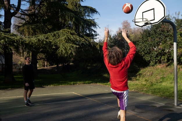 Amis d'âge moyen s'amusant ensemble en jouant au basket