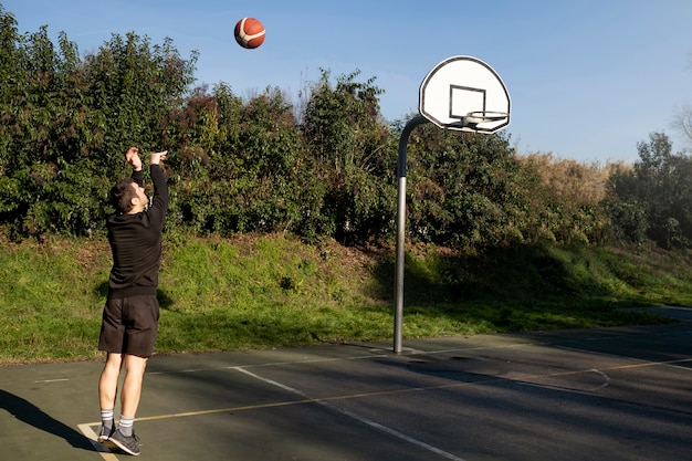 Amis d'âge moyen s'amusant ensemble en jouant au basket